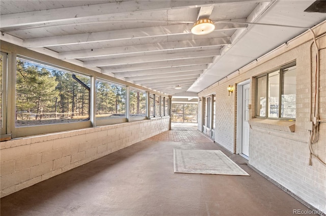 unfurnished sunroom with vaulted ceiling with beams