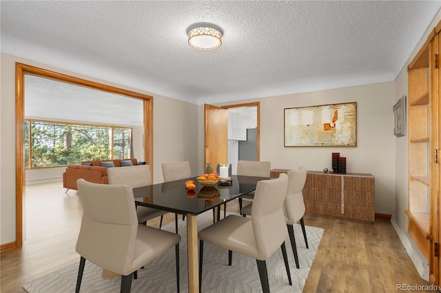 dining space featuring light hardwood / wood-style floors and a textured ceiling