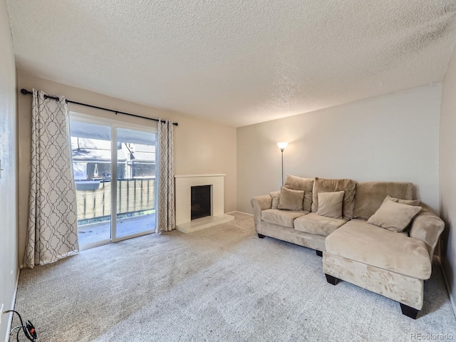 carpeted living room featuring a fireplace with raised hearth and a textured ceiling