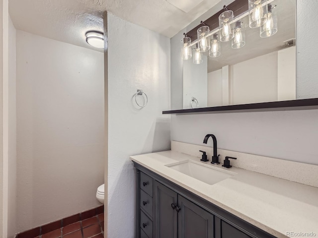 bathroom featuring a textured ceiling, vanity, toilet, and tile patterned floors