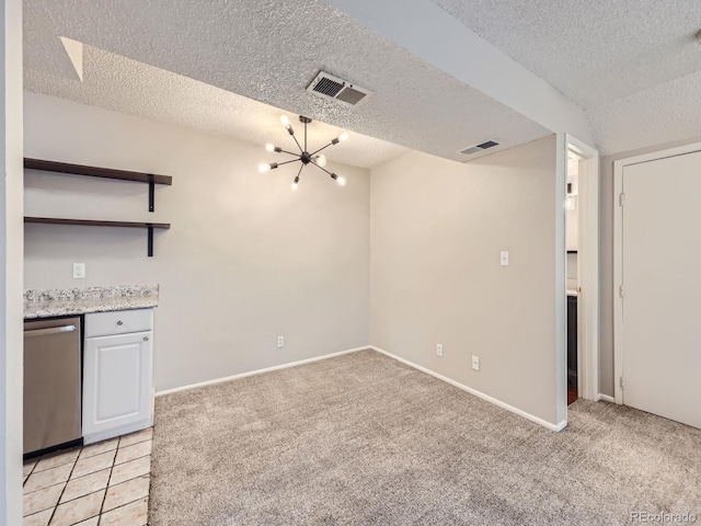 empty room featuring light carpet, a textured ceiling, a chandelier, and visible vents