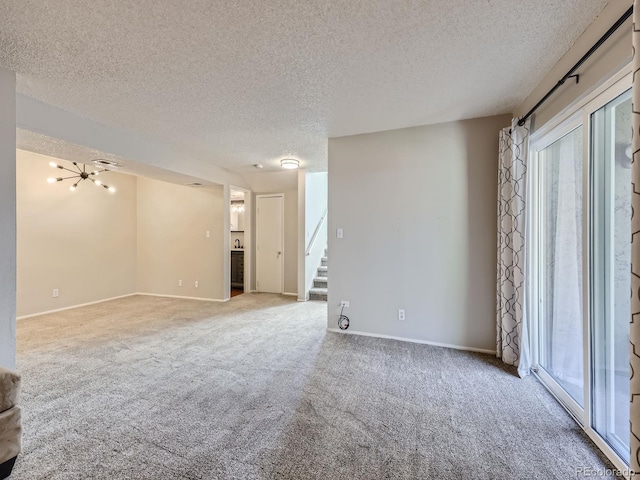 spare room with carpet floors, a textured ceiling, baseboards, and stairs