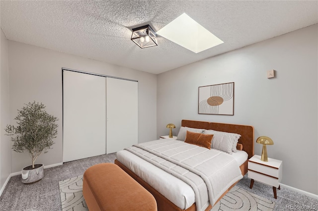 bedroom featuring a textured ceiling, a skylight, carpet flooring, baseboards, and a closet