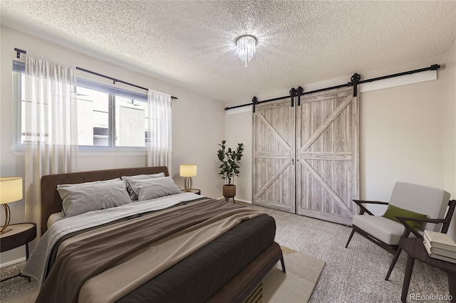 bedroom featuring a barn door, a textured ceiling, and carpet flooring