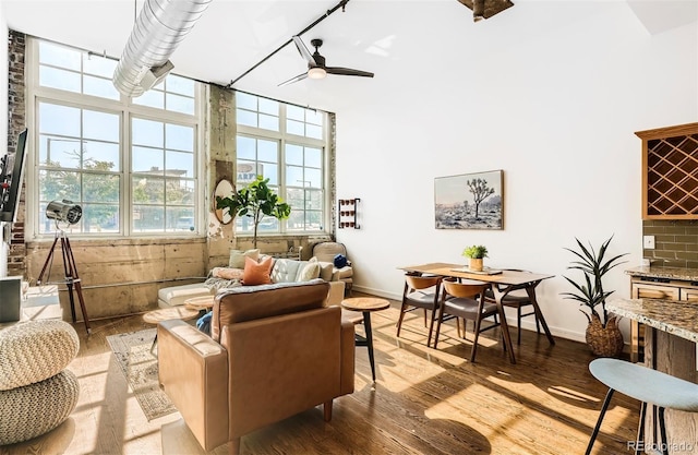 interior space with light hardwood / wood-style floors, a towering ceiling, and ceiling fan