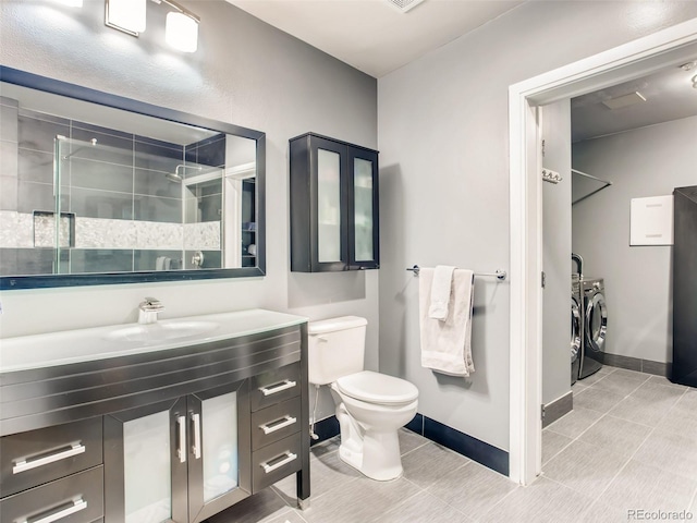 bathroom featuring tiled shower, tile patterned floors, washer and clothes dryer, toilet, and vanity