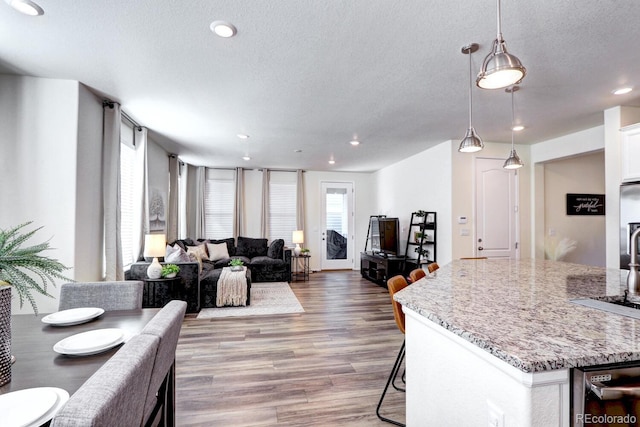 kitchen with white cabinets, light stone counters, open floor plan, wood finished floors, and a textured ceiling