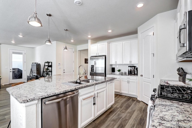 kitchen with dark wood-style floors, a kitchen island with sink, stainless steel appliances, white cabinetry, and a sink