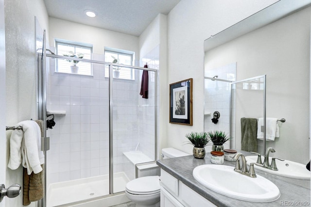 bathroom with vanity, a shower stall, and toilet