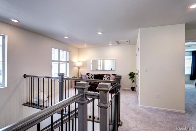 corridor featuring light carpet, recessed lighting, and an upstairs landing