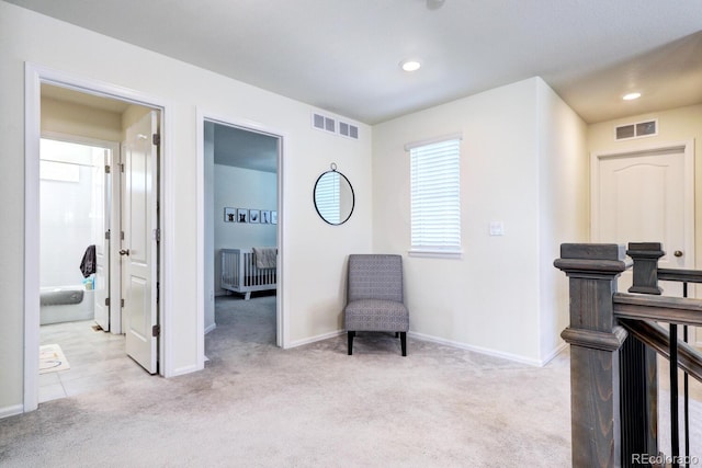 living area with baseboards, visible vents, and light colored carpet