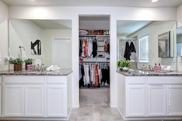 full bathroom with a stall shower, two vanities, and a sink