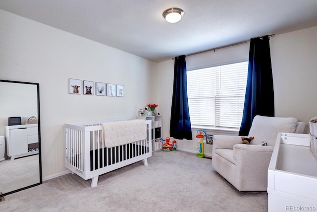 carpeted bedroom featuring a crib, washing machine and dryer, and baseboards