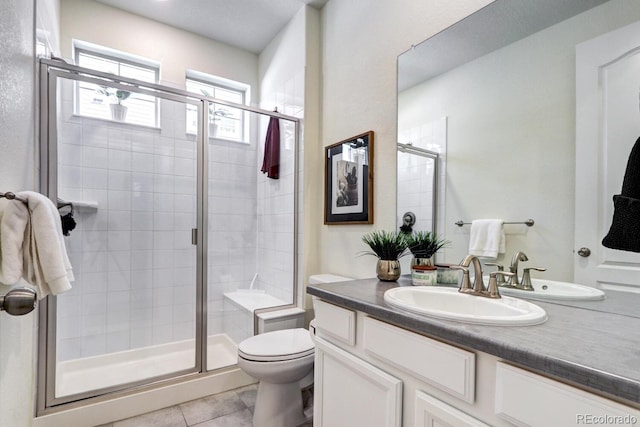 full bathroom with a stall shower, tile patterned flooring, vanity, and toilet