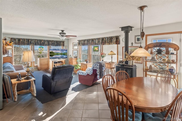 tiled dining area featuring a wood stove, a textured ceiling, and ceiling fan