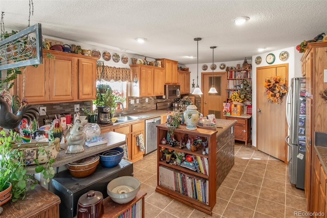 kitchen featuring sink, tasteful backsplash, hanging light fixtures, a textured ceiling, and appliances with stainless steel finishes