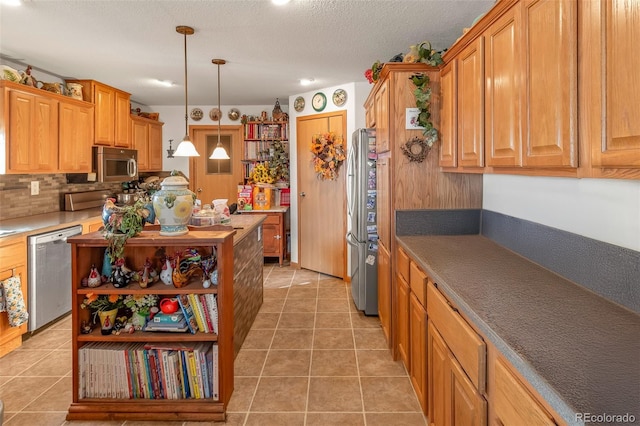 kitchen with tile patterned floors, stainless steel appliances, hanging light fixtures, and a textured ceiling