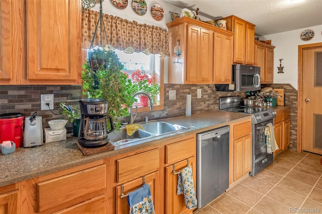 kitchen with sink, a textured ceiling, light tile patterned floors, stainless steel appliances, and backsplash