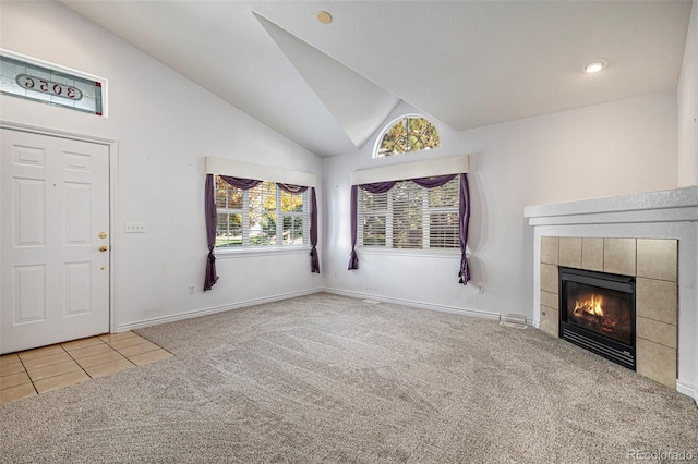 unfurnished living room with high vaulted ceiling, carpet floors, and a tile fireplace