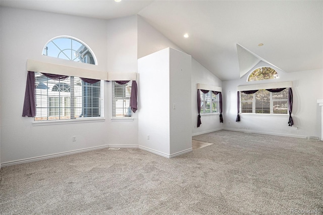 carpeted empty room featuring high vaulted ceiling and plenty of natural light