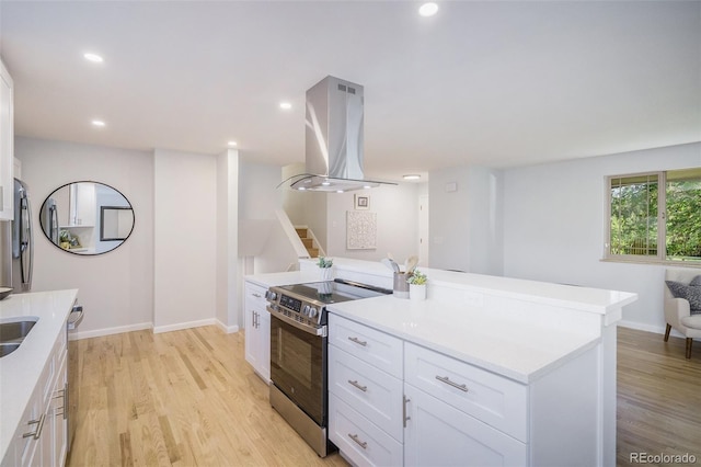 9345 W Iowa Pl, Lakewood, CO 80232 - kitchen with island range hood, stainless steel appliances, white cabinetry, light wood-type flooring, and light countertops