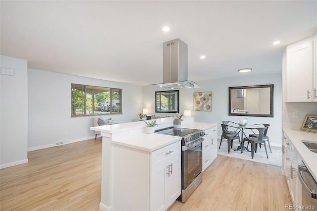 9345 W Iowa Pl, Lakewood, CO 80232 - kitchen featuring appliances with stainless steel finishes, island exhaust hood, light countertops, light wood-type flooring, and white cabinetry