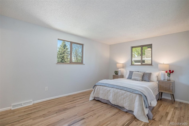 9345 W Iowa Pl, Lakewood, CO 80232 - bedroom featuring light wood-type flooring, multiple windows, a textured ceiling, and baseboards