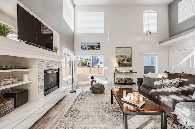 living room featuring light hardwood / wood-style floors, a fireplace, and a towering ceiling