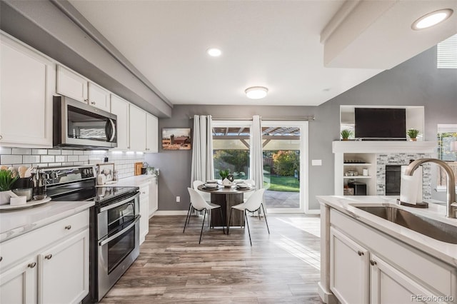 kitchen with hardwood / wood-style floors, sink, white cabinets, appliances with stainless steel finishes, and tasteful backsplash