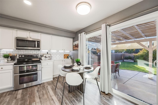 kitchen featuring light hardwood / wood-style floors, decorative backsplash, white cabinets, and stainless steel appliances