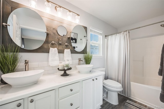 full bathroom with hardwood / wood-style floors, backsplash, shower / tub combo, toilet, and vanity