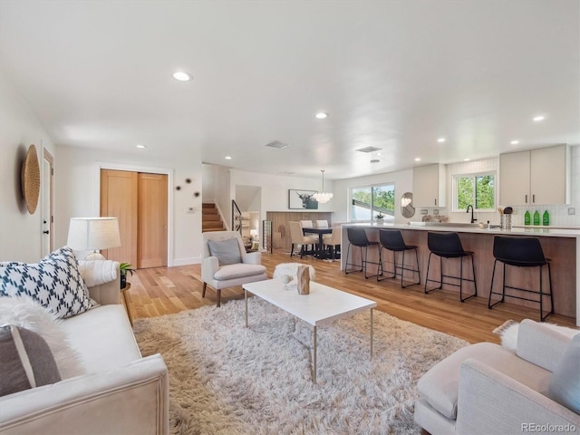 11569 W 27th Ave, Lakewood, CO 80215 - living area featuring stairs, recessed lighting, light wood-style floors, and a chandelier