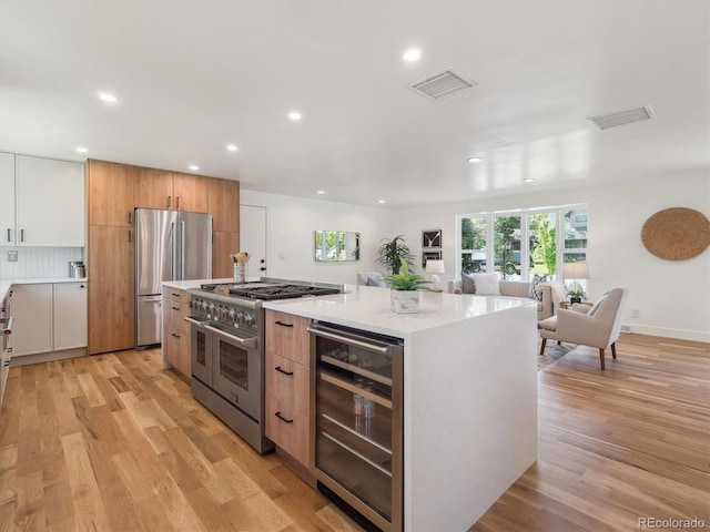 11569 W 27th Ave, Lakewood, CO 80215 - kitchen with appliances with stainless steel finishes, wine cooler, light countertops, light wood-style flooring, and recessed lighting