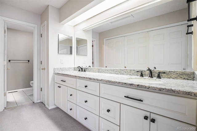 full bathroom with toilet, double vanity, and baseboards