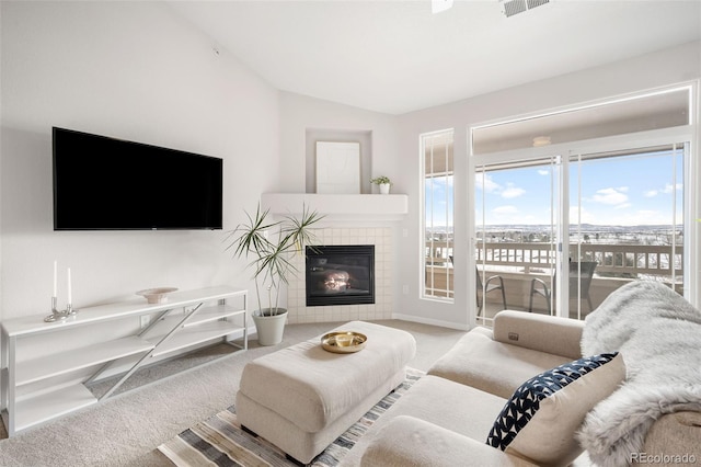 living room with a tile fireplace, vaulted ceiling, and carpet flooring