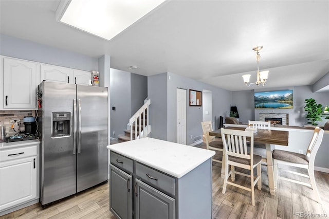 3032 Pony Tracks Dr, Colorado Springs, CO 80922 - kitchen with stainless steel fridge with ice dispenser, white cabinets, light wood-type flooring, open floor plan, and gray cabinets