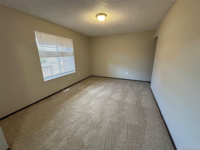 carpeted empty room with a textured ceiling