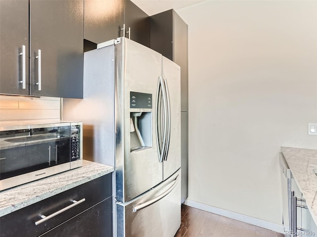 kitchen with stainless steel appliances, dark hardwood / wood-style floors, light stone countertops, and backsplash