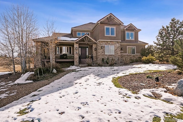 view of front of house with stone siding, covered porch, and stucco siding