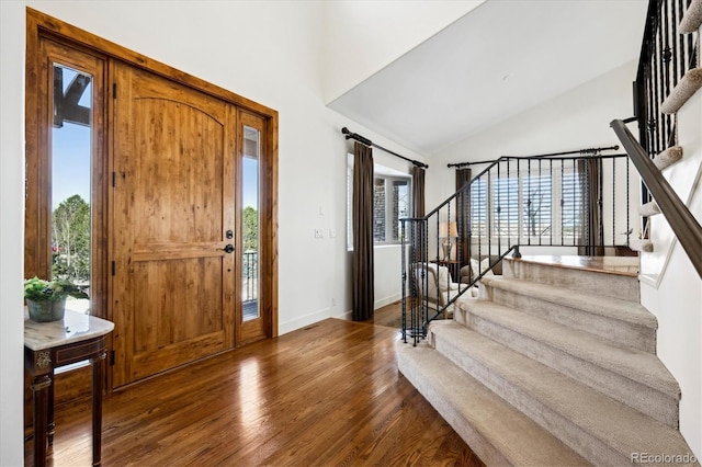 entryway featuring stairs, a healthy amount of sunlight, wood finished floors, and lofted ceiling