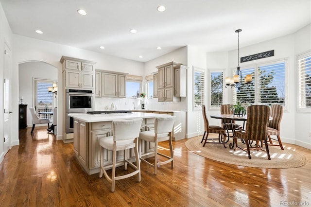 kitchen with arched walkways, a center island, an inviting chandelier, light countertops, and double oven