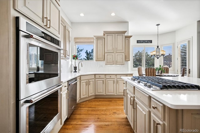 kitchen featuring a notable chandelier, stainless steel appliances, light countertops, a sink, and light wood-type flooring