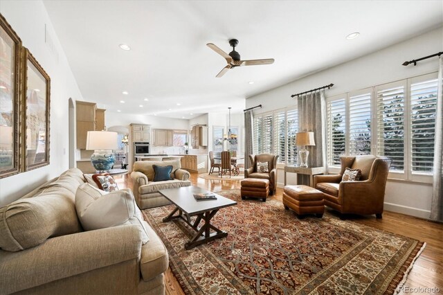 living room with arched walkways, recessed lighting, wood finished floors, a ceiling fan, and baseboards