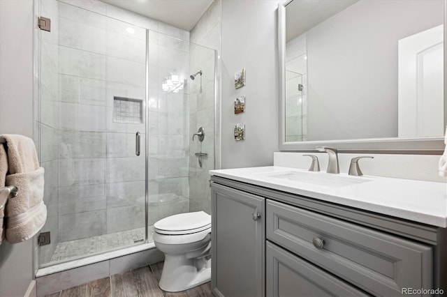 full bathroom featuring toilet, a stall shower, wood finished floors, and vanity