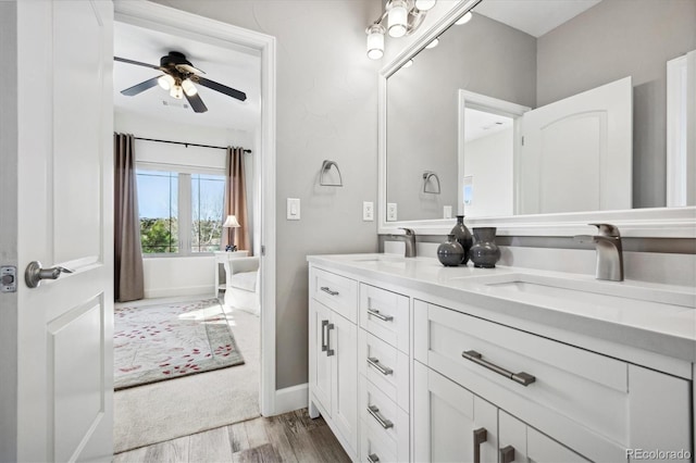 bathroom with ceiling fan, wood finished floors, a sink, and double vanity