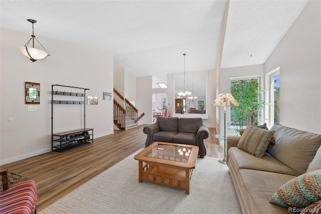 7226 S Eagles Nest Cir, Littleton, CO 80127 - living room featuring wood finished floors, stairs, vaulted ceiling, a chandelier, and baseboards