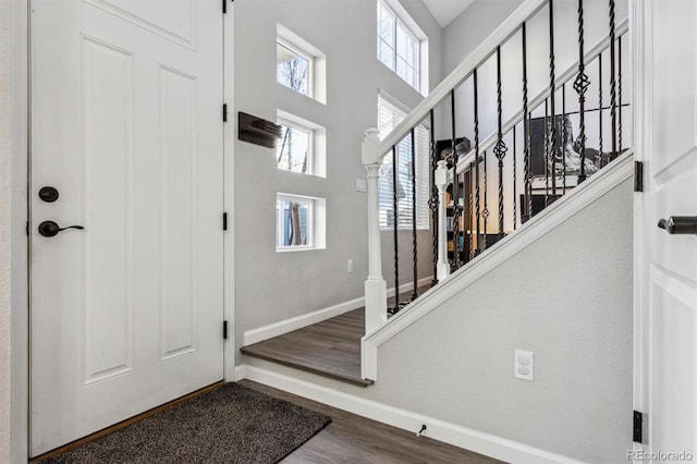 entryway with stairway, baseboards, a high ceiling, and dark wood-style floors