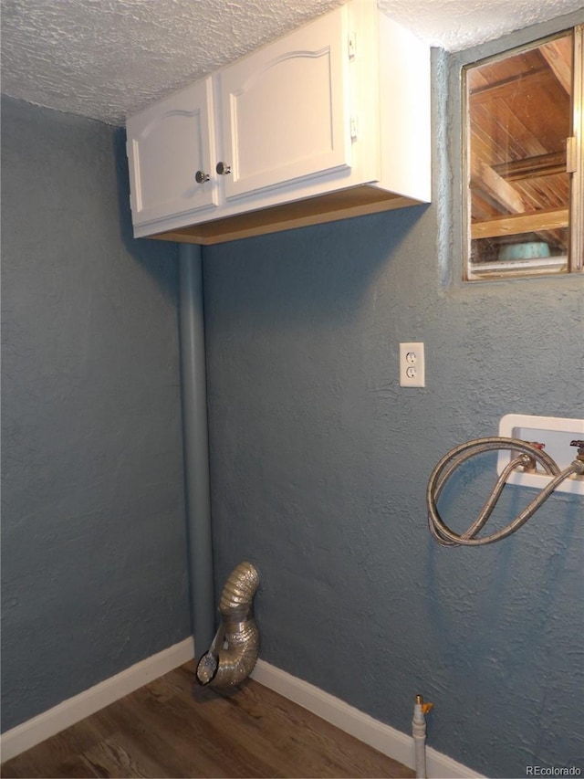 laundry room with a textured wall, hookup for a washing machine, dark wood-style flooring, baseboards, and cabinet space