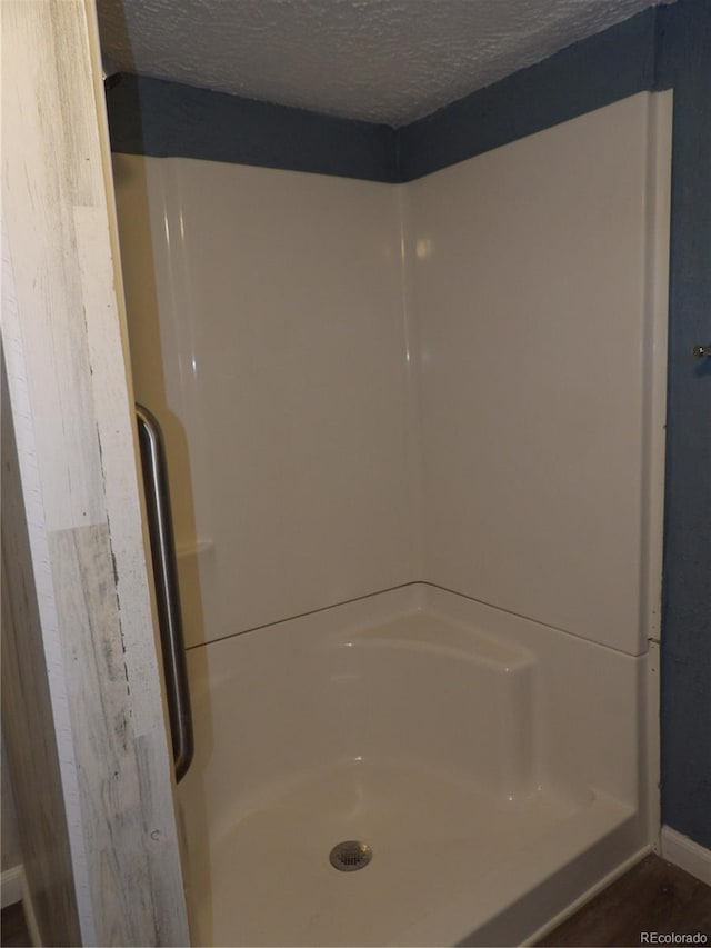 full bath featuring a shower and a textured ceiling