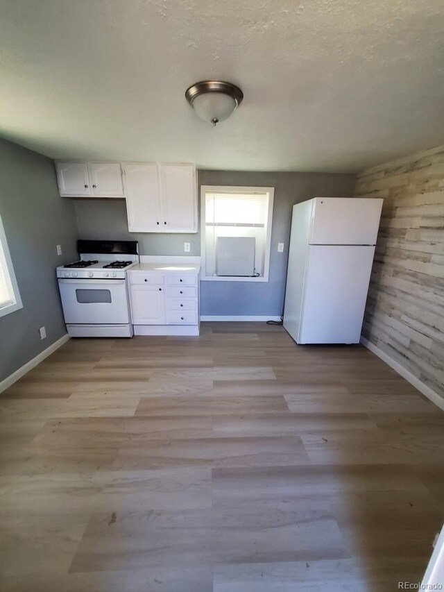 kitchen with white appliances, light countertops, light wood finished floors, and white cabinets